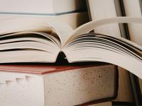 diverse Bücher im Hntergrund - geöffnetes Buch liegt auf geschlossenem