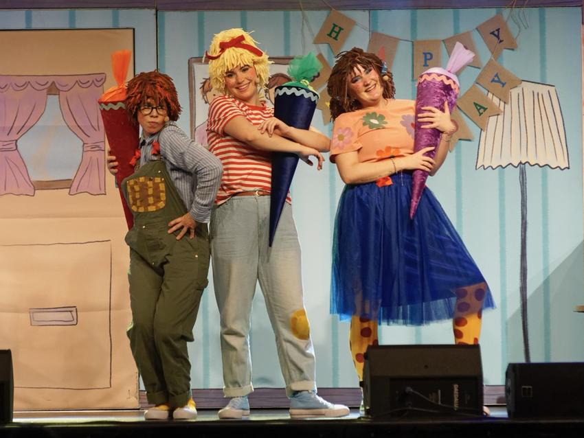 Man sieht 3 Schauspielerinnen, eine ist als Conni verkleidet. Alle haben eine Schultüte in der Hand.