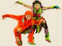 Zwei Schauspielerinnen verkleidet. Eine mit orangem Kostüm, eine mit grünem Kostüm.